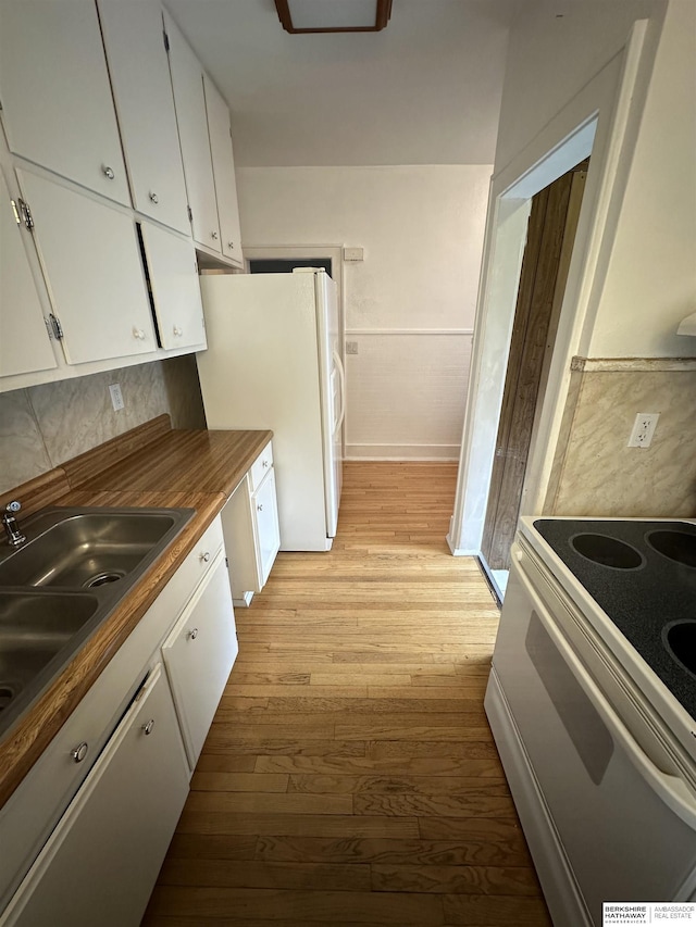 2002 Warren St, Bellevue, NE 68005 - kitchen with white appliances, a sink, light wood-style floors, white cabinets, and wainscoting