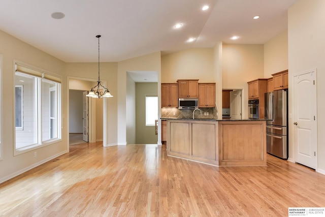 1414 S 189th Ct, Omaha, NE 68130 - kitchen featuring stainless steel appliances, dark countertops, backsplash, light wood finished floors, and decorative light fixtures