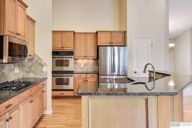 1414 S 189th Ct, Omaha, NE 68130 - kitchen featuring appliances with stainless steel finishes, a sink, light wood finished floors, dark stone countertops, and a high ceiling