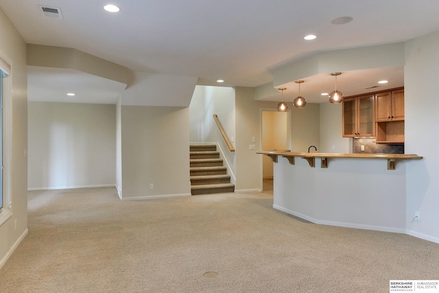 1414 S 189th Ct, Omaha, NE 68130 - kitchen with a peninsula, a kitchen breakfast bar, light colored carpet, recessed lighting, and brown cabinetry
