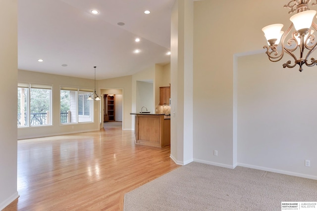 1414 S 189th Ct, Omaha, NE 68130 - unfurnished living room with a chandelier, baseboards, recessed lighting, light wood-style floors, and a sink
