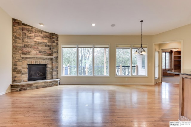 1414 S 189th Ct, Omaha, NE 68130 - unfurnished living room with light wood-style floors, a stone fireplace, baseboards, and lofted ceiling