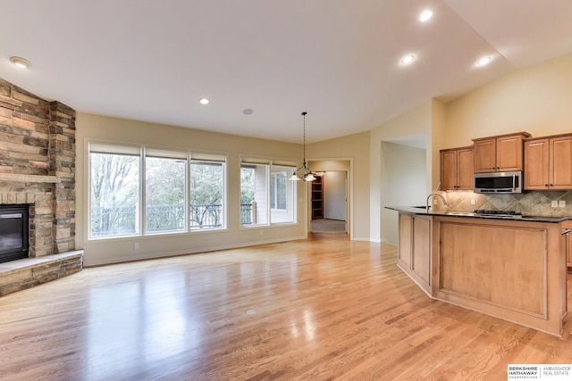 1414 S 189th Ct, Omaha, NE 68130 - kitchen featuring stainless steel microwave, dark countertops, open floor plan, tasteful backsplash, and a fireplace