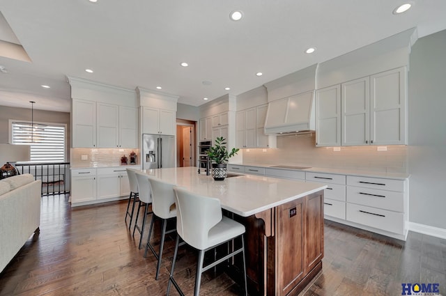 8947 Himark Ln, Lincoln, NE 68526 - kitchen featuring appliances with stainless steel finishes, custom range hood, dark wood finished floors, white cabinets, and decorative backsplash