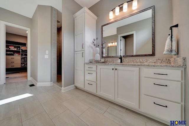 8947 Himark Ln, Lincoln, NE 68526 - bathroom with a tile shower, vanity, a walk in closet, and tile patterned flooring
