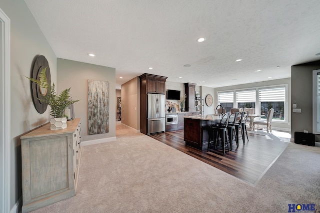 8947 Himark Ln, Lincoln, NE 68526 - kitchen with stainless steel fridge, dark carpet, recessed lighting, a kitchen island with sink, and a breakfast bar area