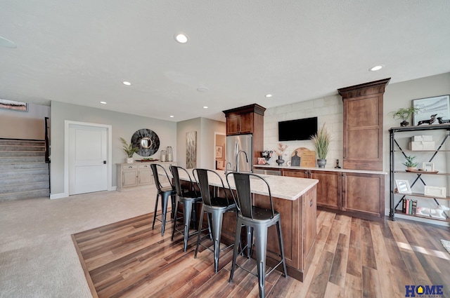 8947 Himark Ln, Lincoln, NE 68526 - kitchen featuring freestanding refrigerator, a kitchen breakfast bar, an island with sink, recessed lighting, and baseboards