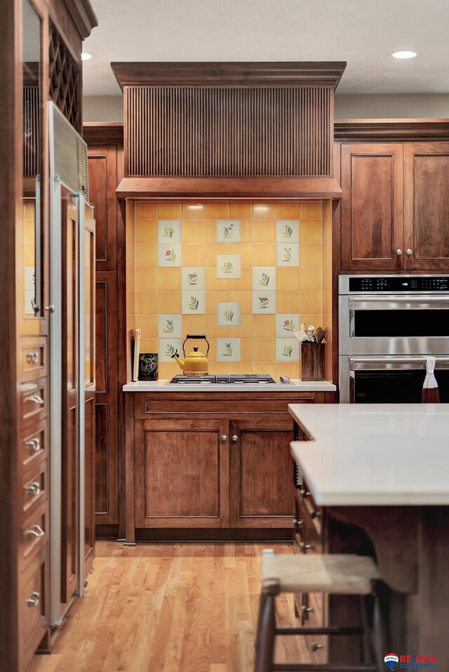 9900 Van Dorn St, Lincoln, NE 68520 - kitchen with appliances with stainless steel finishes, backsplash, custom exhaust hood, light countertops, and light wood finished floors