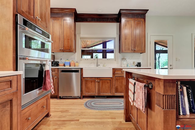 9900 Van Dorn St, Lincoln, NE 68520 - kitchen featuring a sink, stainless steel appliances, light wood-style flooring, light countertops, and brown cabinets