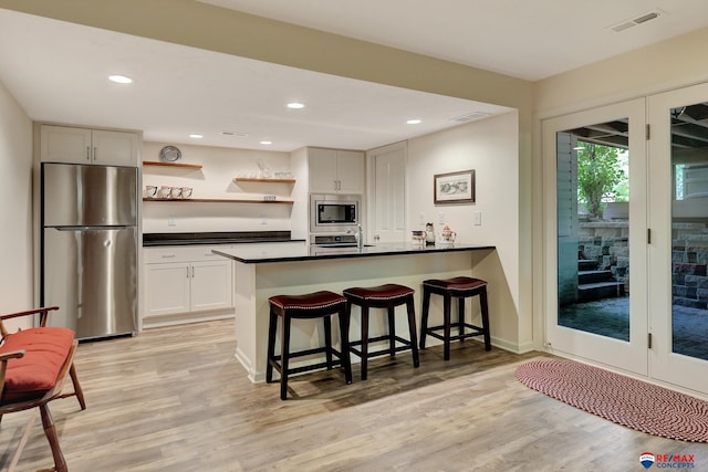 9900 Van Dorn St, Lincoln, NE 68520 - kitchen featuring stainless steel appliances, dark countertops, open shelves, light wood-style floors, and a kitchen breakfast bar