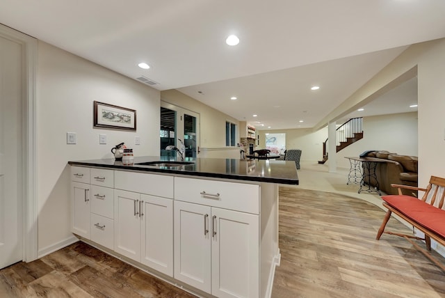 9900 Van Dorn St, Lincoln, NE 68520 - kitchen with light wood-style floors, a peninsula, open floor plan, dark countertops, and white cabinetry