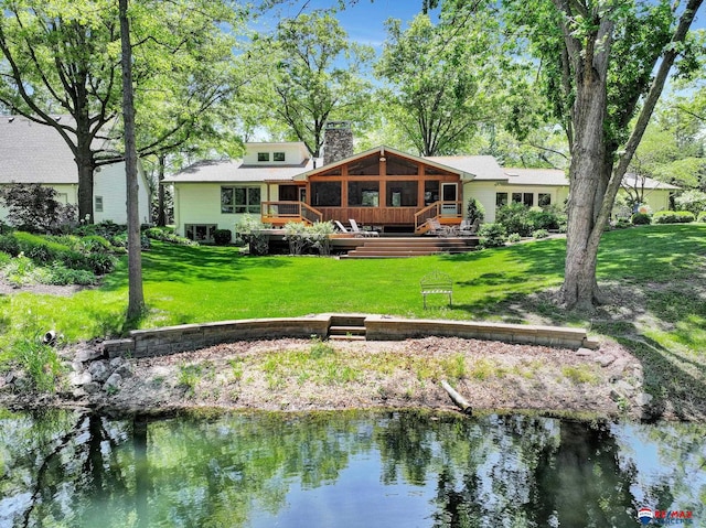 9900 Van Dorn St, Lincoln, NE 68520 - rear view of house featuring a chimney, a deck with water view, a lawn, and a sunroom