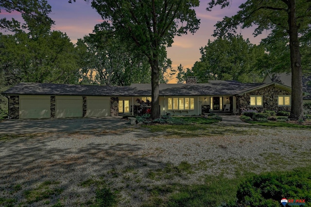 9900 Van Dorn St, Lincoln, NE 68520 - view of front of property featuring driveway, a garage, stone siding, and a chimney