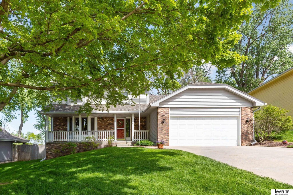 6219 S 79th Cir, Ralston, NE 68127 - view of front facade with brick siding, covered porch, an attached garage, and driveway