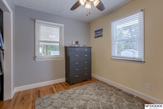 bedroom with light wood finished floors, baseboards, and a ceiling fan
