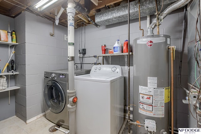 washroom featuring water heater, concrete block wall, and washer and dryer