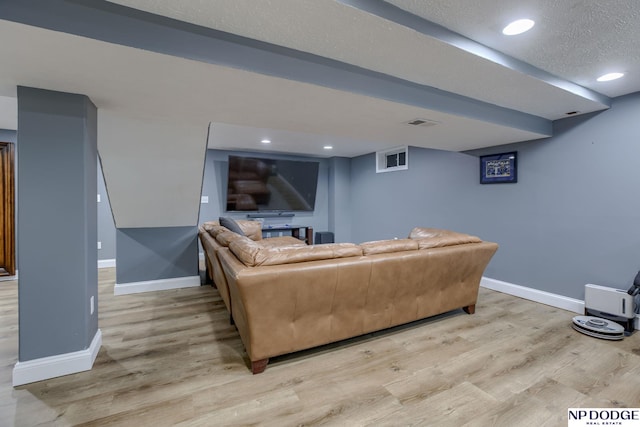 living area featuring baseboards, light wood-type flooring, recessed lighting, and a textured ceiling