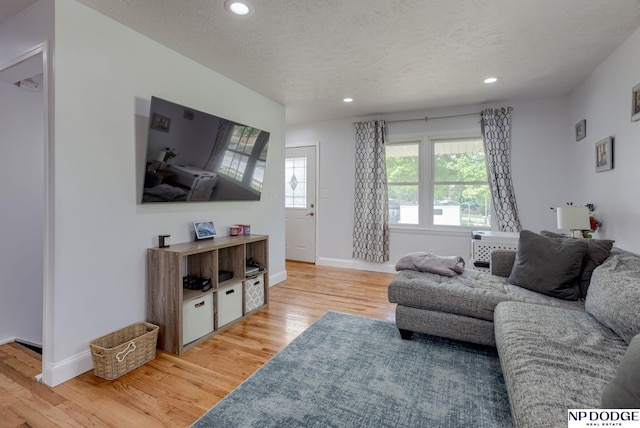 living room with light wood-style flooring, recessed lighting, baseboards, and a textured ceiling