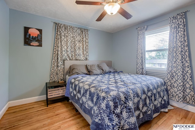bedroom with light wood finished floors, baseboards, and a ceiling fan