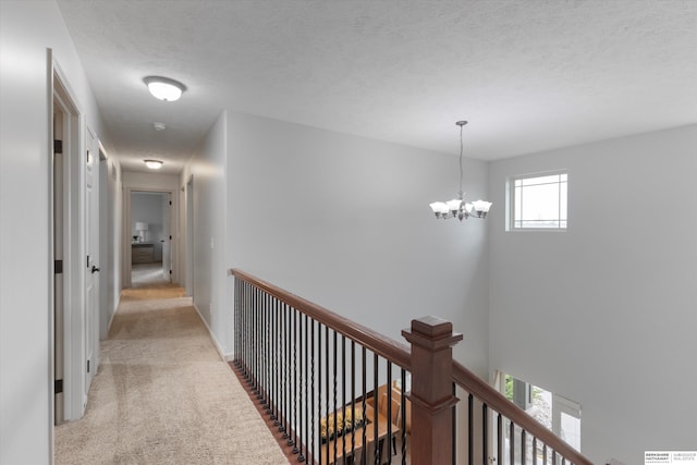 18652 Van Camp Dr, Omaha, NE 68130 - corridor featuring light colored carpet, an upstairs landing, a chandelier, a textured ceiling, and baseboards