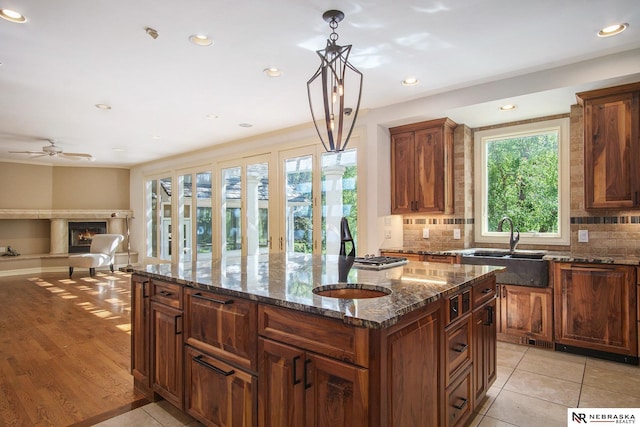 1125 Stone Creek Dr, Blair, NE 68008 - kitchen with a sink, a lit fireplace, decorative backsplash, a kitchen island, and recessed lighting