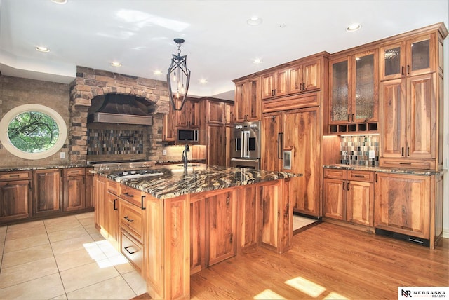 1125 Stone Creek Dr, Blair, NE 68008 - kitchen with stainless steel appliances, dark stone countertops, decorative backsplash, glass insert cabinets, and an island with sink