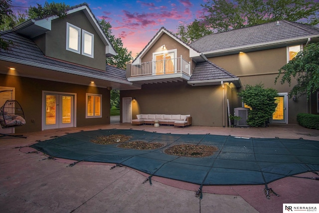 1125 Stone Creek Dr, Blair, NE 68008 - back of property at dusk featuring a balcony, stucco siding, outdoor lounge area, a tiled roof, and central AC