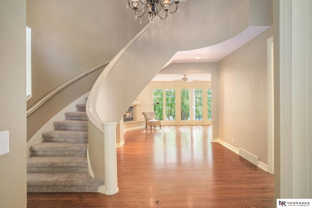 1125 Stone Creek Dr, Blair, NE 68008 - staircase featuring wood finished floors, a towering ceiling, a chandelier, baseboards, and a ceiling fan