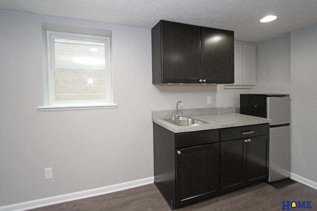 1701 N 73rd St, Lincoln, NE 68505 - kitchen featuring a sink, baseboards, dark wood-type flooring, light countertops, and freestanding refrigerator