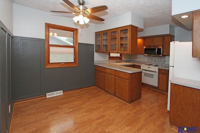 1701 N 73rd St, Lincoln, NE 68505 - kitchen with white range with electric stovetop, stainless steel microwave, brown cabinetry, light countertops, and light wood-style flooring