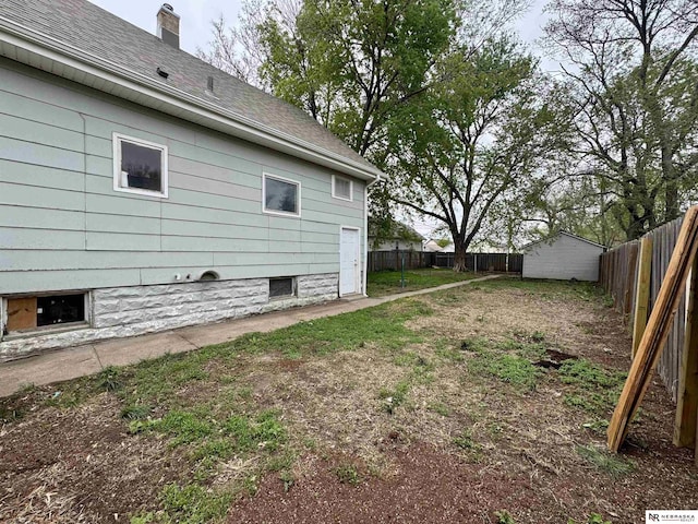 1300 Claremont St, Lincoln, NE 68508 - view of side of property featuring a fenced backyard, an outdoor structure, a shed, a shingled roof, and a chimney
