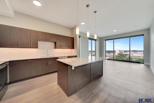 1125 Q St Unit 1401, Lincoln, NE 68508 - kitchen with a sink, light countertops, a center island, backsplash, and stainless steel electric range oven