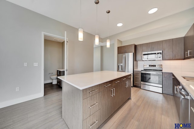 1125 Q St Unit 1401, Lincoln, NE 68508 - kitchen featuring appliances with stainless steel finishes, tasteful backsplash, light wood finished floors, a center island, and light countertops
