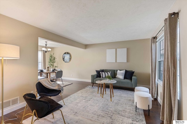 3909 N 147th St, Omaha, NE 68116 - living area featuring healthy amount of natural light, a textured ceiling, baseboards, dark wood-style flooring, and a chandelier