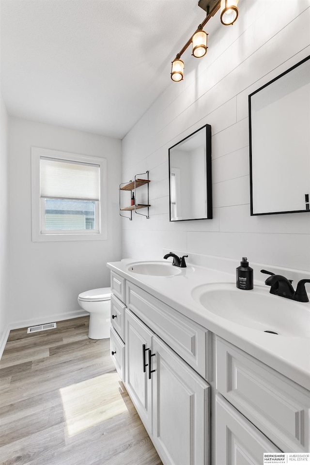 221 Lindale Cir, Hickman, NE 68372 - full bathroom with double vanity, toilet, baseboards, and wood finished floors