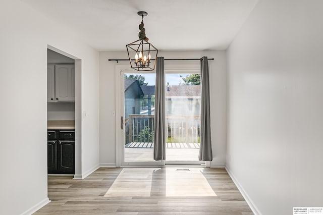221 Lindale Cir, Hickman, NE 68372 - unfurnished dining area with a chandelier, light wood finished floors, and baseboards