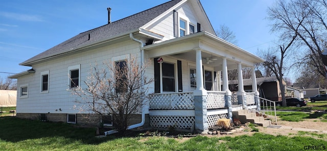 942 Manatt St, Lincoln, NE 68521 - view of side of home with a porch, a ceiling fan, roof with shingles, and a lawn