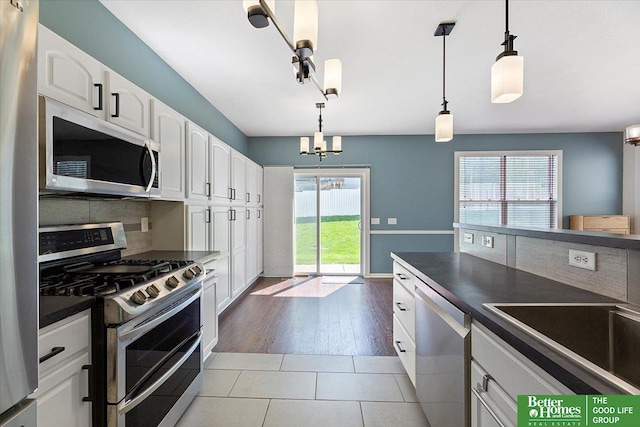 kitchen featuring appliances with stainless steel finishes, dark countertops, white cabinets, tasteful backsplash, and decorative light fixtures