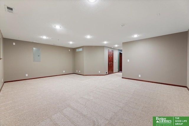 empty room with light colored carpet, baseboards, electric panel, and recessed lighting