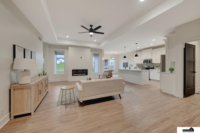 8600 S 50th Ct, Lincoln, NE 68516 - living room with a tray ceiling, a ceiling fan, recessed lighting, light wood-style flooring, and a fireplace