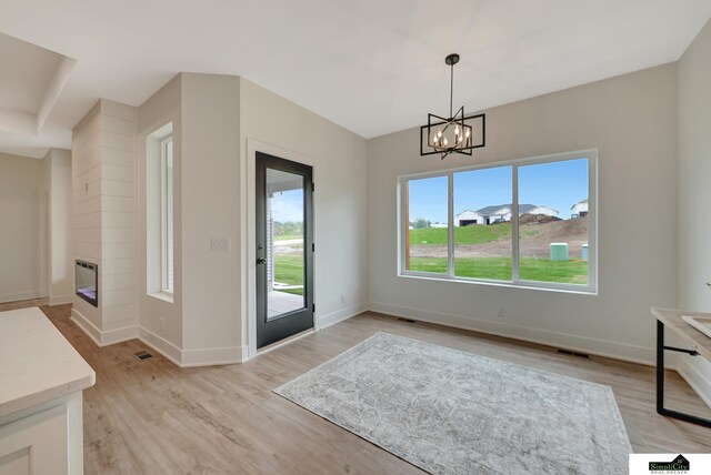 8600 S 50th Ct, Lincoln, NE 68516 - unfurnished dining area featuring light wood-type flooring, a chandelier, baseboards, and a glass covered fireplace