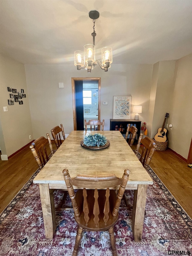 dining area with a chandelier, wood finished floors, and baseboards