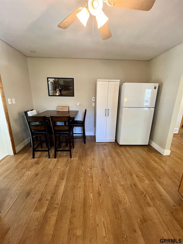 dining space featuring wood finished floors, baseboards, and a ceiling fan
