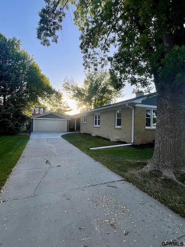 single story home with a detached garage, brick siding, and a front yard