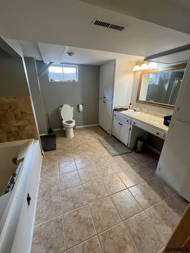 bathroom featuring tile patterned floors, toilet, vanity, and a tub to relax in