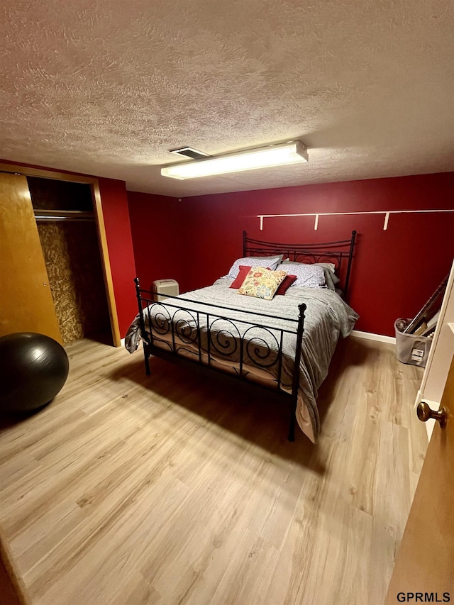 bedroom featuring wood finished floors, a textured ceiling, and baseboards