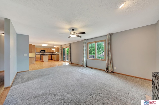 7910 Red Oak Rd, Lincoln, NE 68516 - unfurnished living room with ceiling fan, light carpet, a textured ceiling, and baseboards