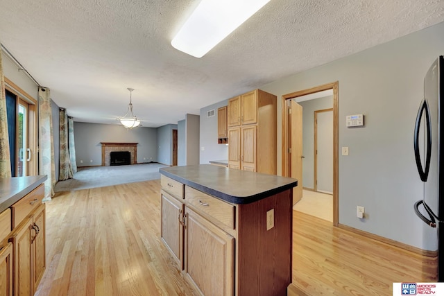 7910 Red Oak Rd, Lincoln, NE 68516 - kitchen with freestanding refrigerator, light wood-style floors, dark countertops, a textured ceiling, and a kitchen island