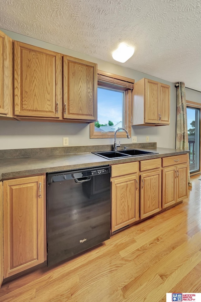 7910 Red Oak Rd, Lincoln, NE 68516 - kitchen with black dishwasher, a sink, a textured ceiling, light wood finished floors, and dark countertops