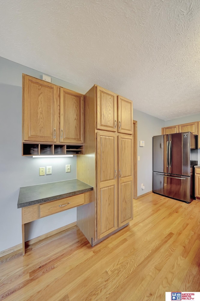 7910 Red Oak Rd, Lincoln, NE 68516 - kitchen with freestanding refrigerator, light wood-style flooring, dark countertops, and a textured ceiling